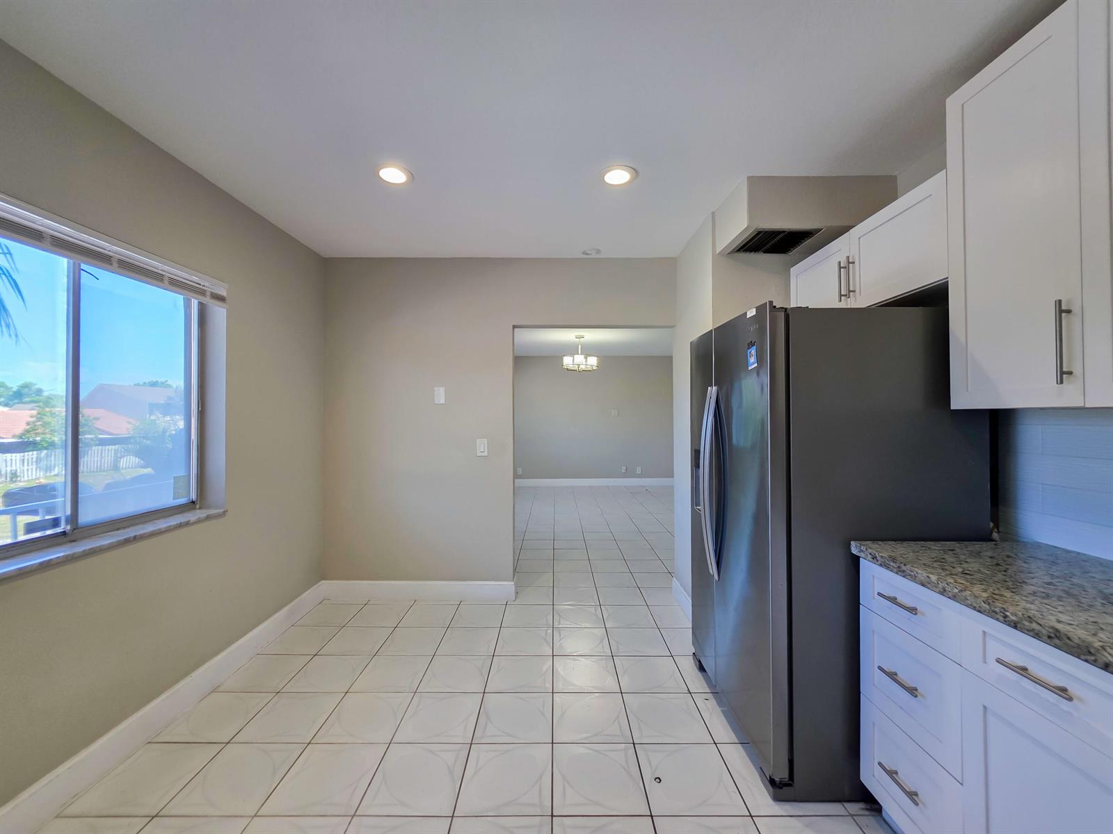A kitchen area features white cabinets, a stainless steel refrigerator, and tile flooring — 6289 Lear Drive # 203, Lake Worth FL 33462, LAKE WORTH, FL