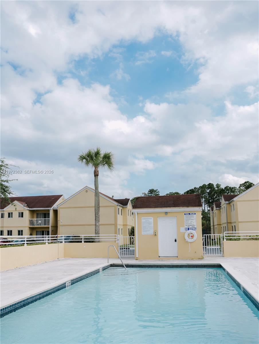 A swimming pool sits in front of a small utility building and apartment complex — 13820 SW 112th St # 204, Miami FL 33186, MIAMI, FL