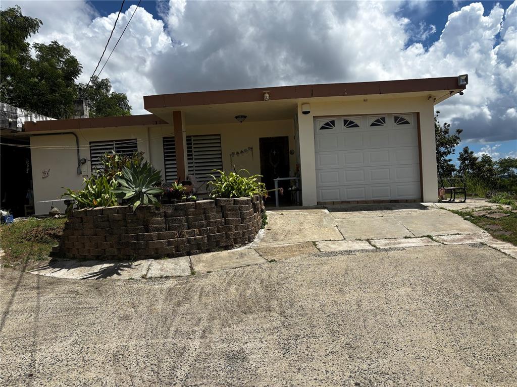 A single-story house with a garage, a concrete driveway, and a stone planter in front — Km 1.9 842 CARRETERA, SAN JUAN, PR