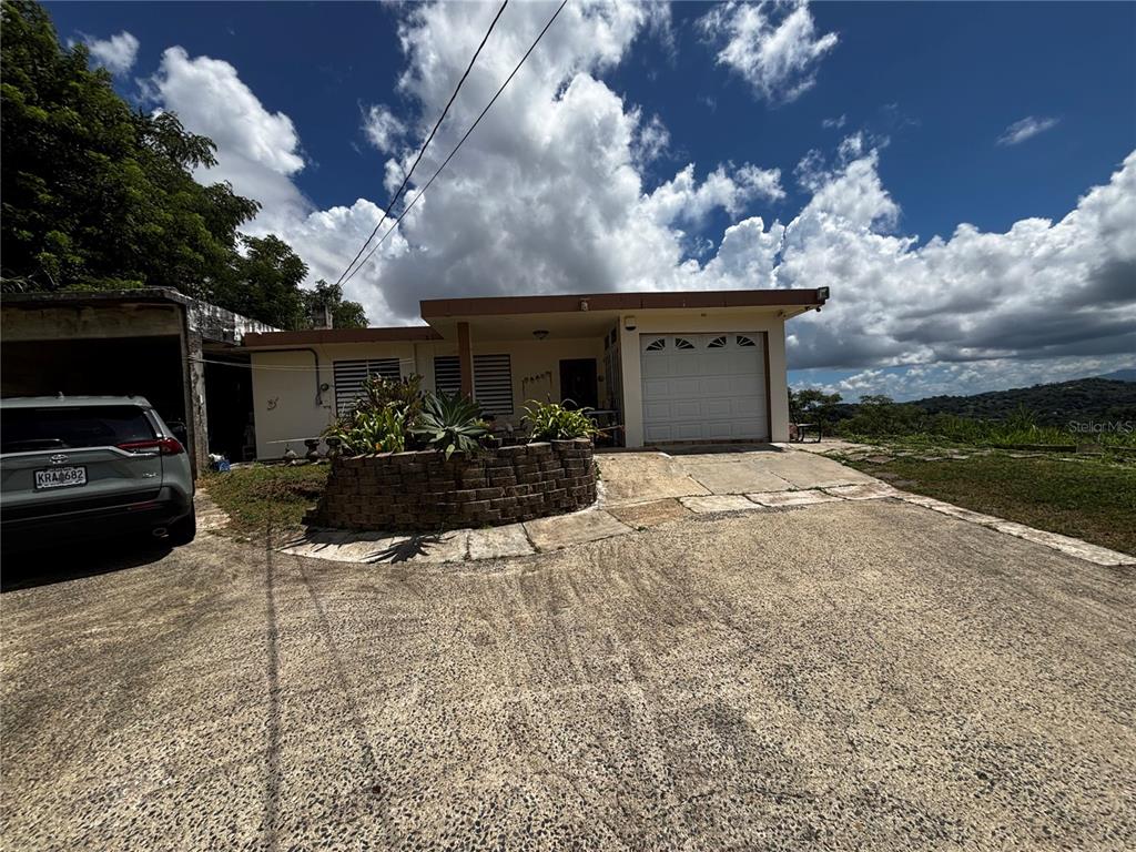 A single-story house with a garage and a concrete driveway under a cloudy sky — Km 1.9 842 CARRETERA, SAN JUAN, PR