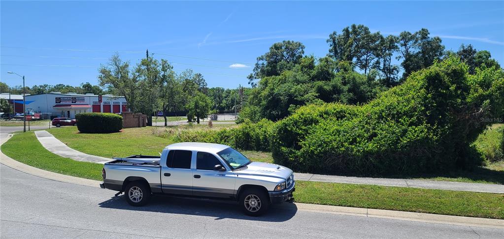 A silver pickup truck is parked on a street next to a vacant, overgrown lot — 0 WOOD DOVE, LOTS 1.2.3.&4 AVENUE, TARPON SPRINGS, FL