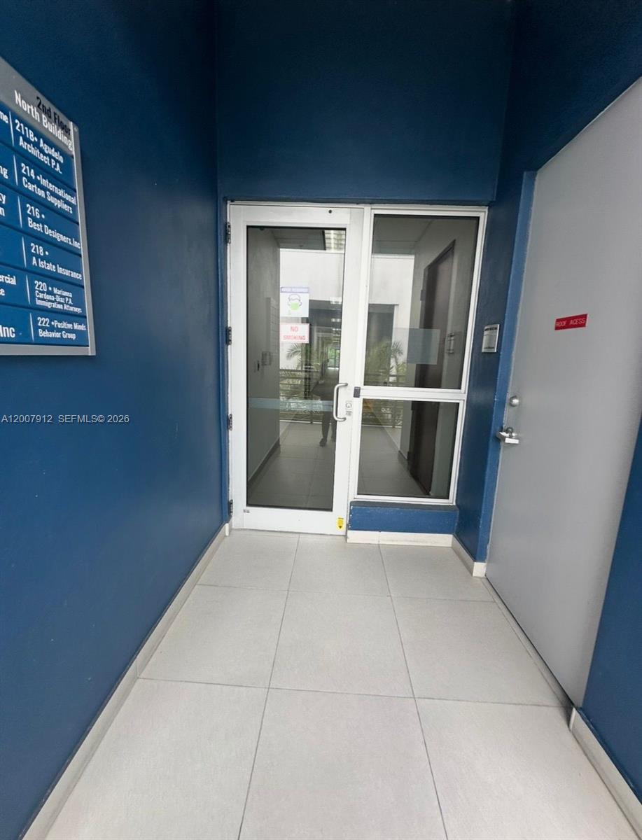 A hallway with a glass door, a gray utility door, and a building directory sign — 1500 NW 89th Ct # 217, Doral FL 33172, DORAL, FL