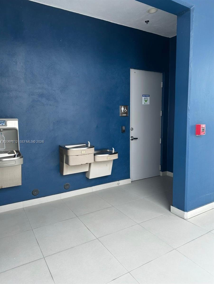 A blue wall features a water fountain station next to a door with restroom signage — 1500 NW 89th Ct # 217, Doral FL 33172, DORAL, FL