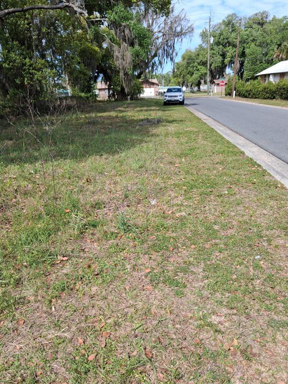 A grassy, undeveloped residential lot sits adjacent to a paved road with a parked car — 552 NE GURLEY AVENUE, LAKE CITY, FL
