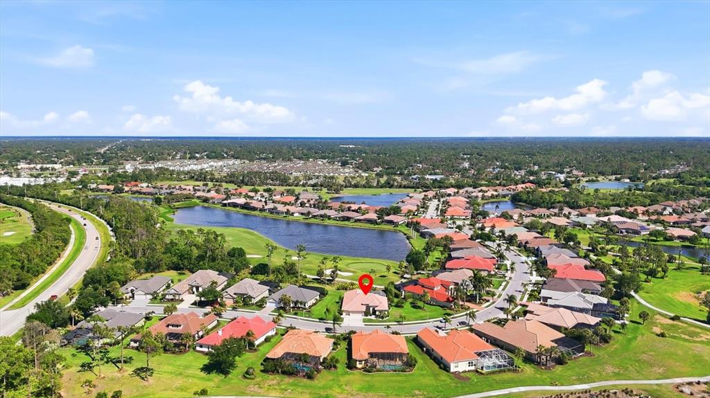 An aerial view shows a residential neighborhood with houses surrounding a lake and golf course — 1166 EAGLES FLIGHT WAY, NORTH PORT, FL