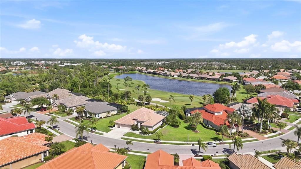 An aerial view shows a suburban neighborhood with houses surrounding a lake and golf course — 1166 EAGLES FLIGHT WAY, NORTH PORT, FL