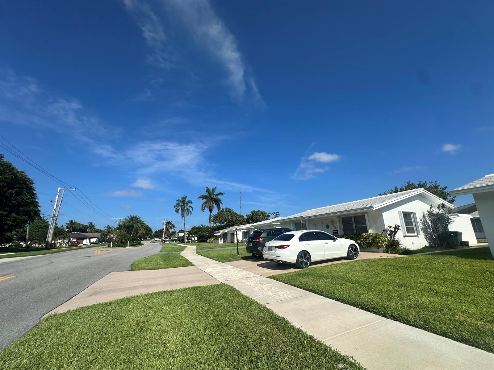 A white house with a driveway and two parked cars sits along a suburban street — 806 Ocean Drive, Boynton Beach FL 33426, BOYNTON BEACH, FL