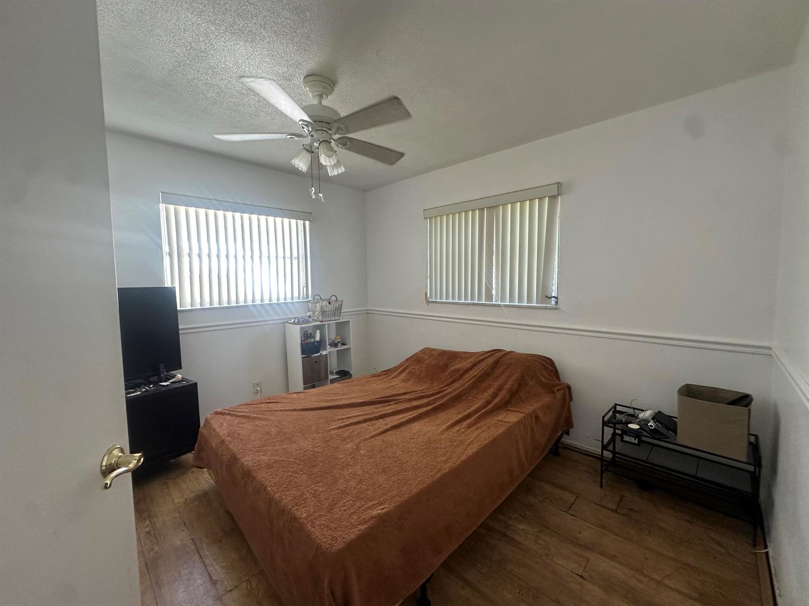 A bedroom features a bed with a brown blanket, two windows, and wood-look flooring — 806 Ocean Drive, Boynton Beach FL 33426, BOYNTON BEACH, FL