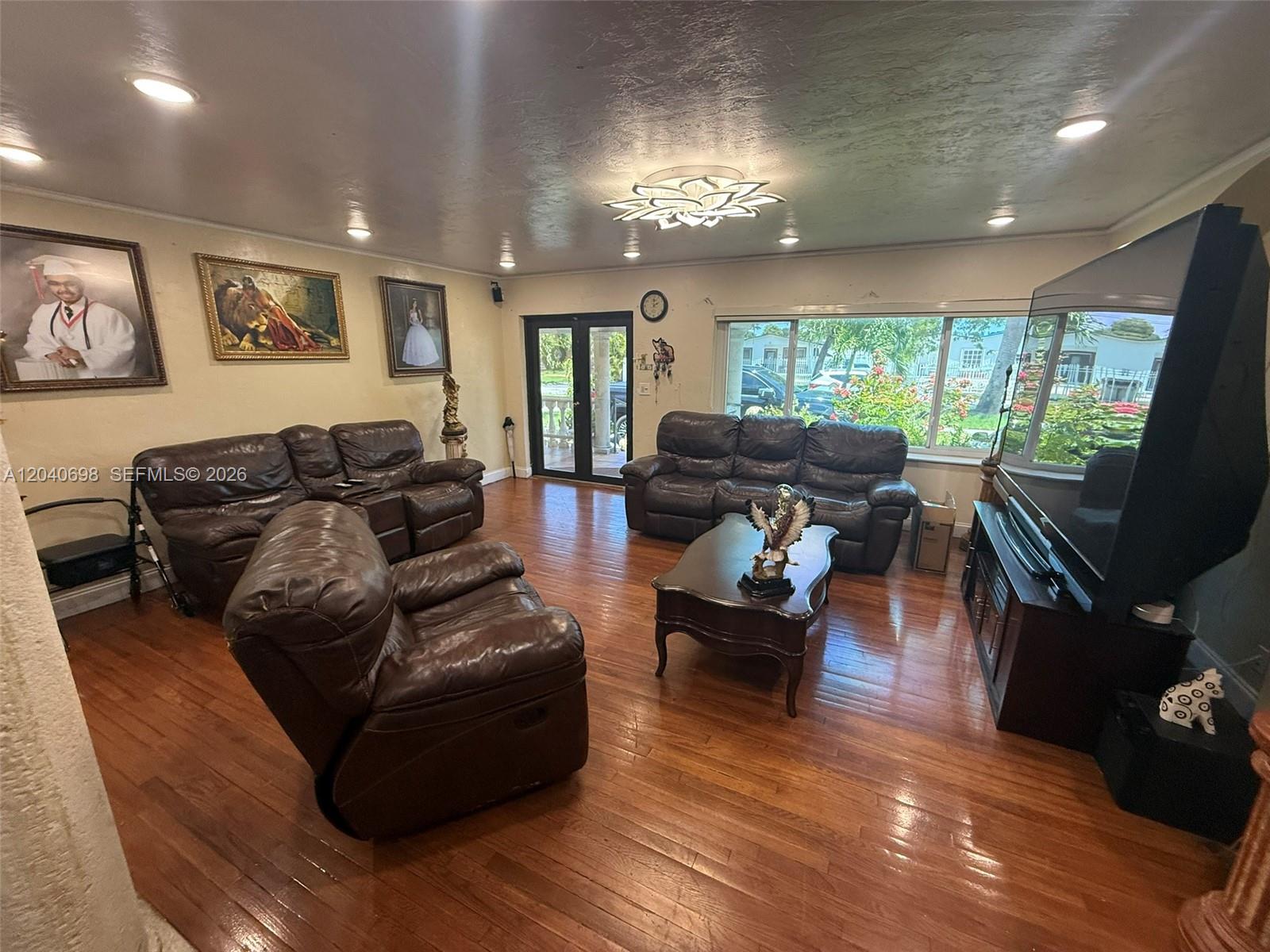 A living room features dark leather furniture, hardwood floors, and a large television — 202 To To Lo Chee Dr, Hialeah FL 33010, HIALEAH, FL