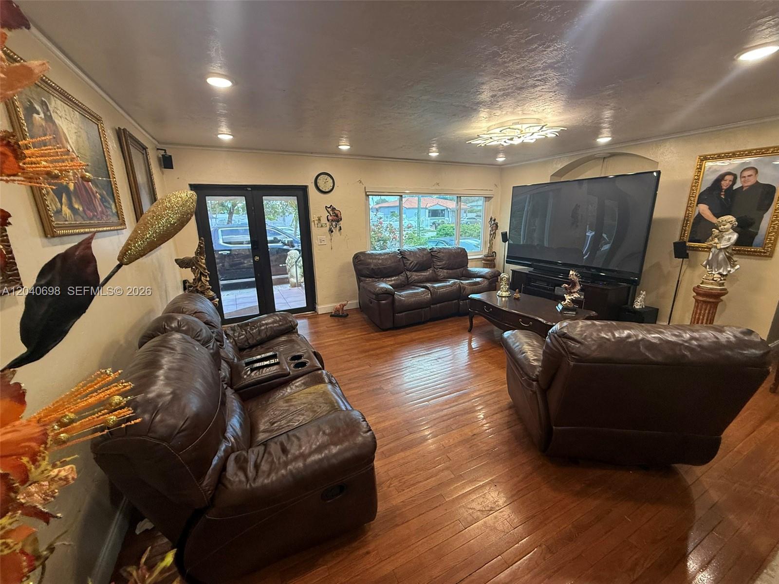 A living room features brown leather furniture, hardwood floors, and a large television — 202 To To Lo Chee Dr, Hialeah FL 33010, HIALEAH, FL