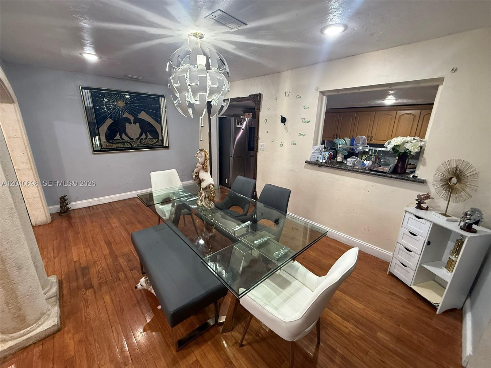A dining room features a glass table, mixed seating, a chandelier, and a pass-through window — 202 To To Lo Chee Dr, Hialeah FL 33010, HIALEAH, FL