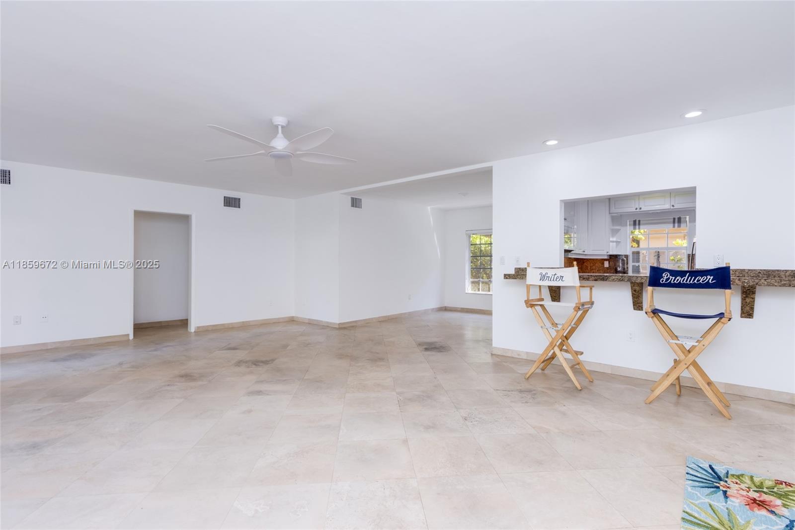 An open-concept living area features white walls, tile flooring, a ceiling fan, and a breakfast bar — 60 Park Dr # C, Bal Harbour FL 33154, BAL HARBOUR, FL