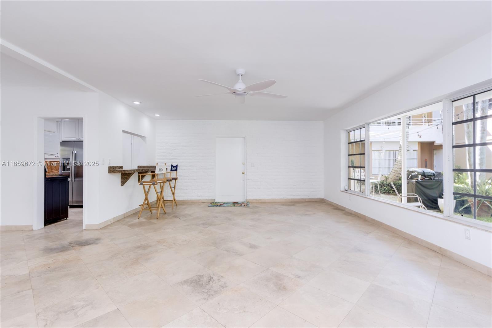A bright, tiled room features a white brick wall, a ceiling fan, and a breakfast bar — 60 Park Dr # C, Bal Harbour FL 33154, BAL HARBOUR, FL