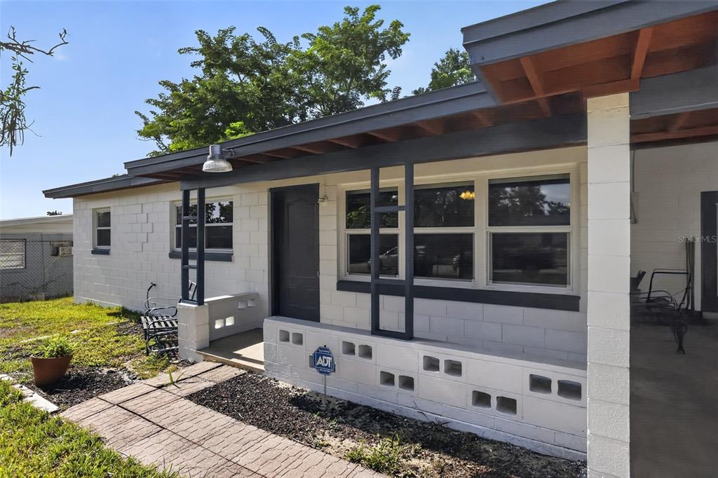 A single-story house with white concrete block walls, a dark trim, and a covered porch — 6120 W RIDGEWOOD AVENUE, ORLANDO, FL