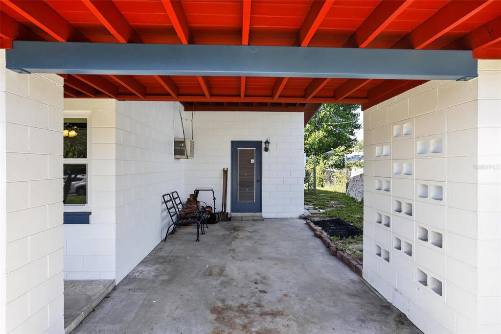 A covered concrete patio features white block walls, a red ceiling, and a decorative screen — 6120 W RIDGEWOOD AVENUE, ORLANDO, FL