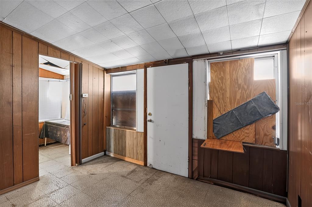 A room with wood-paneled walls, a drop ceiling, and a boarded-up window — 6120 W RIDGEWOOD AVENUE, ORLANDO, FL