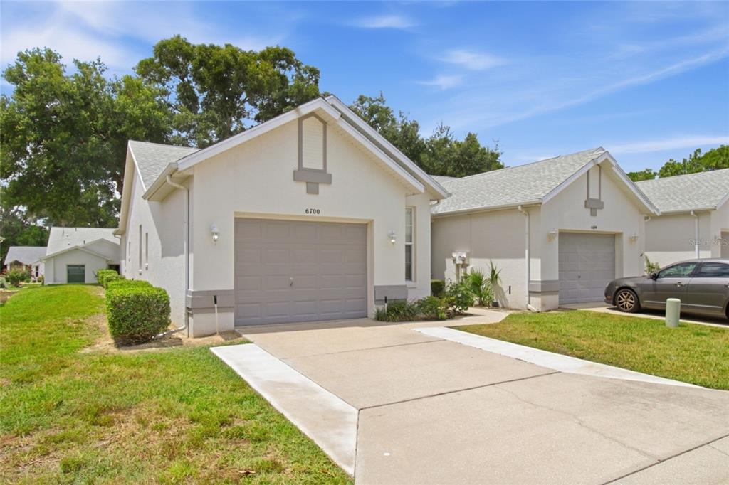 A beige single-story house with a gray garage door and a concrete driveway — 6700 E KINGSBURY LANE, INVERNESS, FL