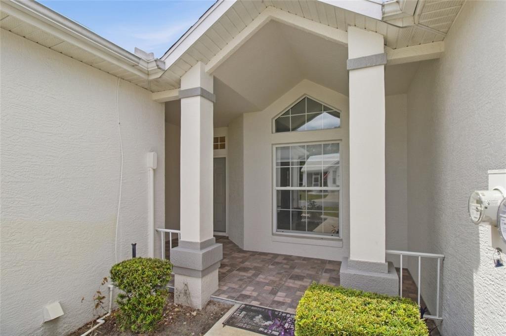 A covered entryway features two white columns, a tiled floor, and a large window — 6700 E KINGSBURY LANE, INVERNESS, FL