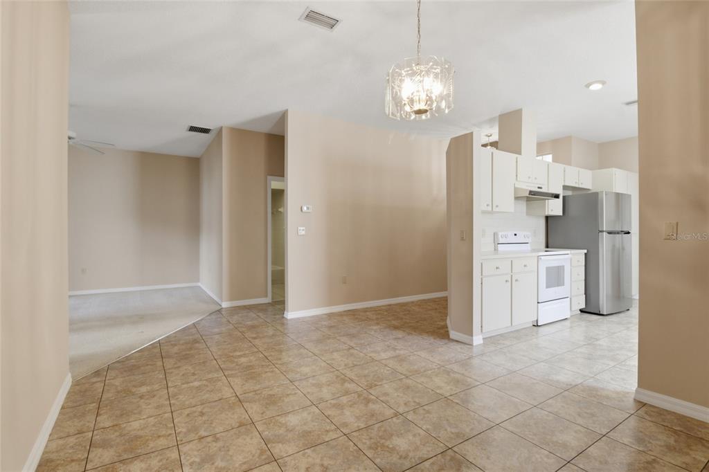 An open-concept kitchen and dining area features tile flooring, white cabinets, and stainless appliances — 6700 E KINGSBURY LANE, INVERNESS, FL