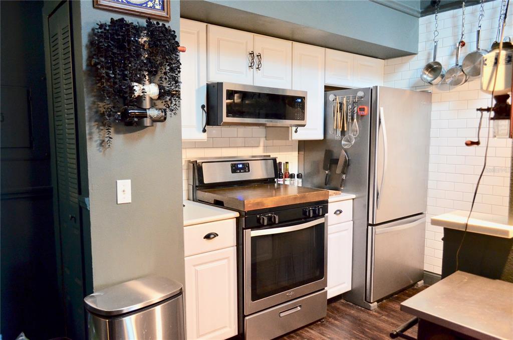 A kitchen features white cabinets, stainless steel appliances, a subway tile backsplash, and dark walls — 101 N HILL AVENUE UNIT 5, DELAND, FL
