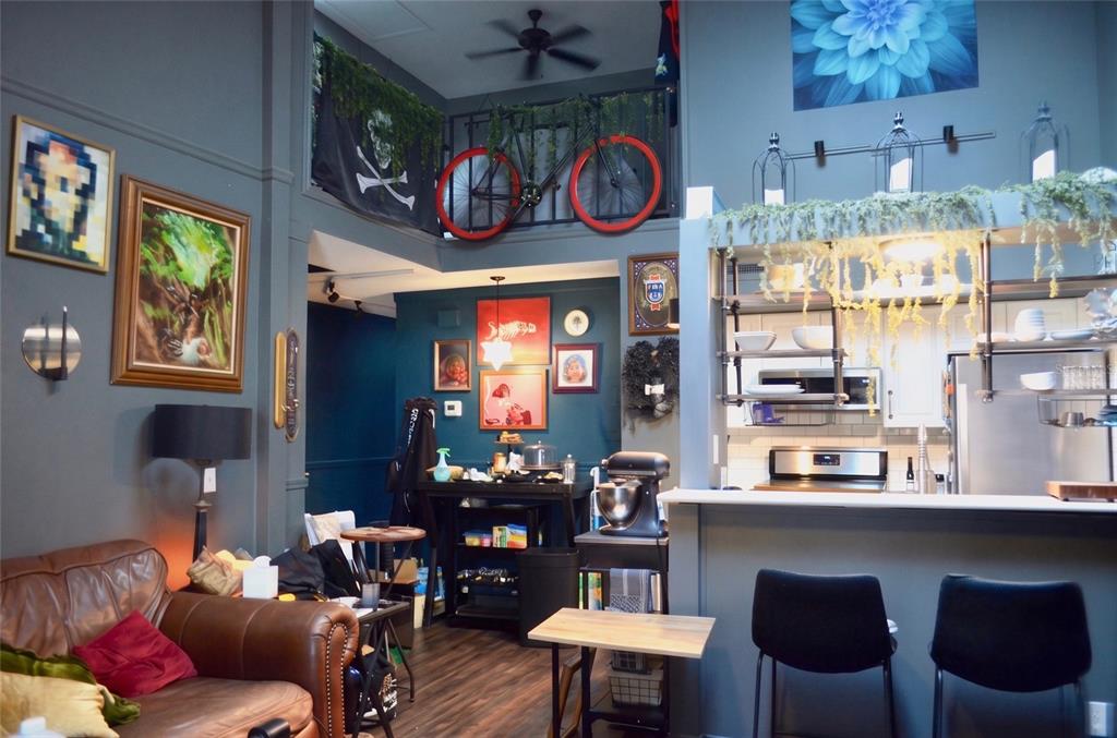 A living room and kitchen area with dark walls, a lofted balcony, and a bicycle — 101 N HILL AVENUE UNIT 5, DELAND, FL