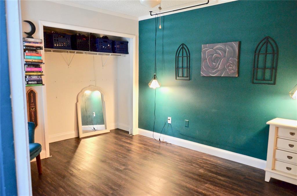 A bedroom features a teal accent wall, a closet with storage bins, and wood-look flooring — 101 N HILL AVENUE UNIT 5, DELAND, FL