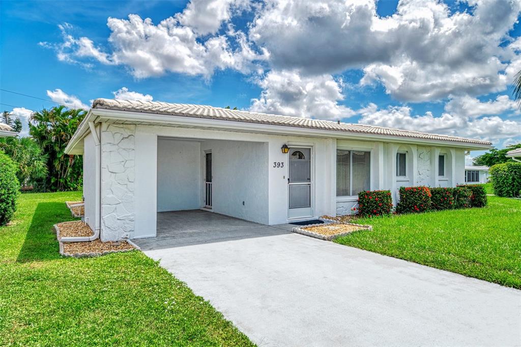 A white single-story house with a carport, a front door, and a manicured lawn — 393 CIRCLEWOOD DRIVE UNIT Z3, VENICE, FL