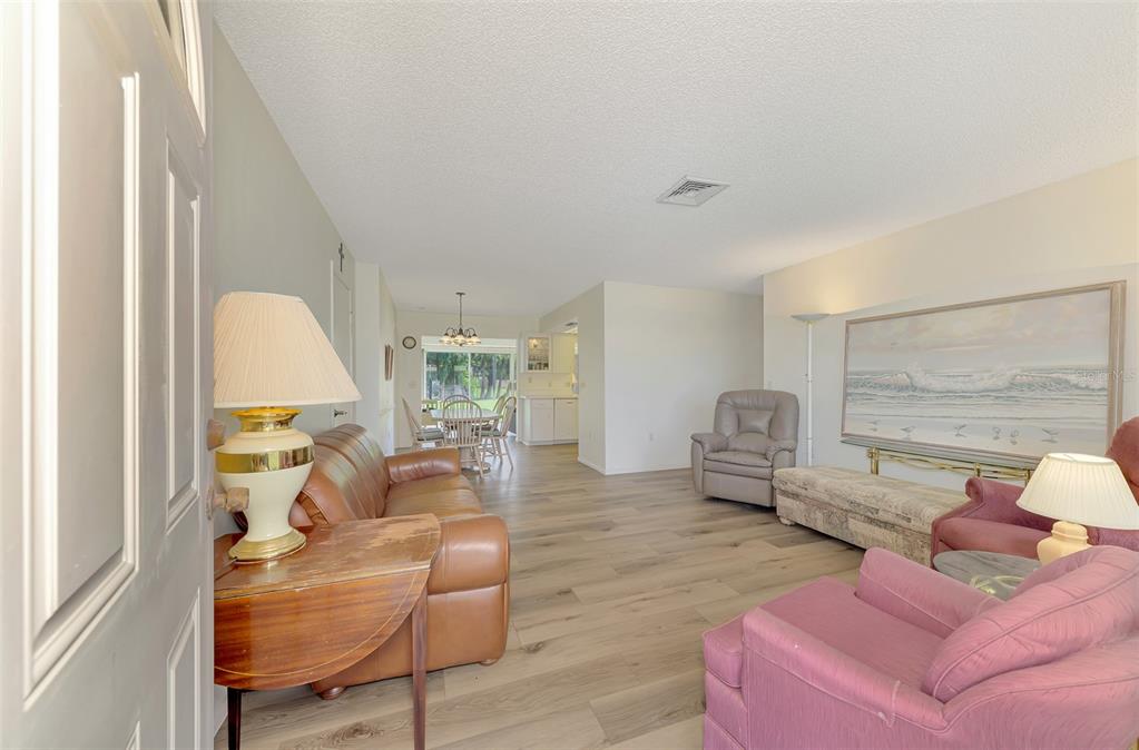 A living room with wood-look flooring, a leather sofa, and a view into the dining area — 393 CIRCLEWOOD DRIVE UNIT Z3, VENICE, FL