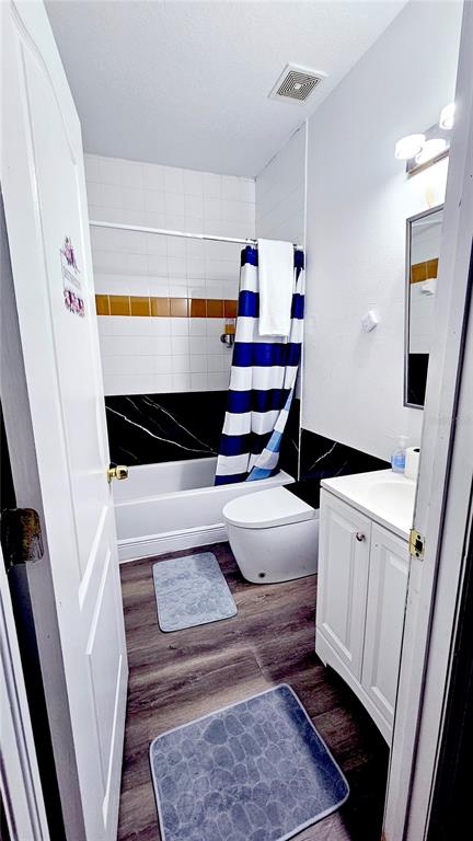 A bathroom features a white vanity, a toilet, and a shower with a blue-striped curtain — 13612 N 21ST STREET UNIT 2, TAMPA, FL