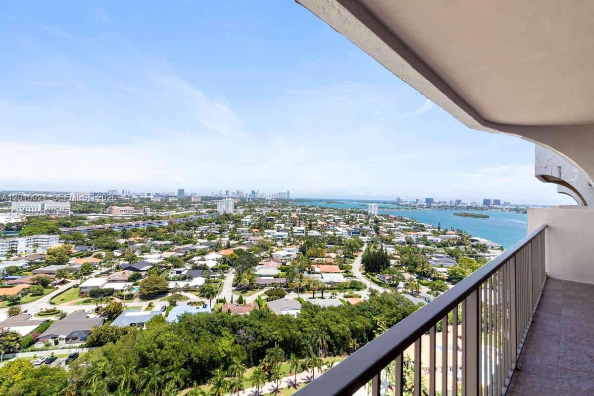 A high-angle view from a balcony overlooking a suburban neighborhood, lush trees, and water — 1800 NE 114th St, Miami FL 33181, MIAMI, FL