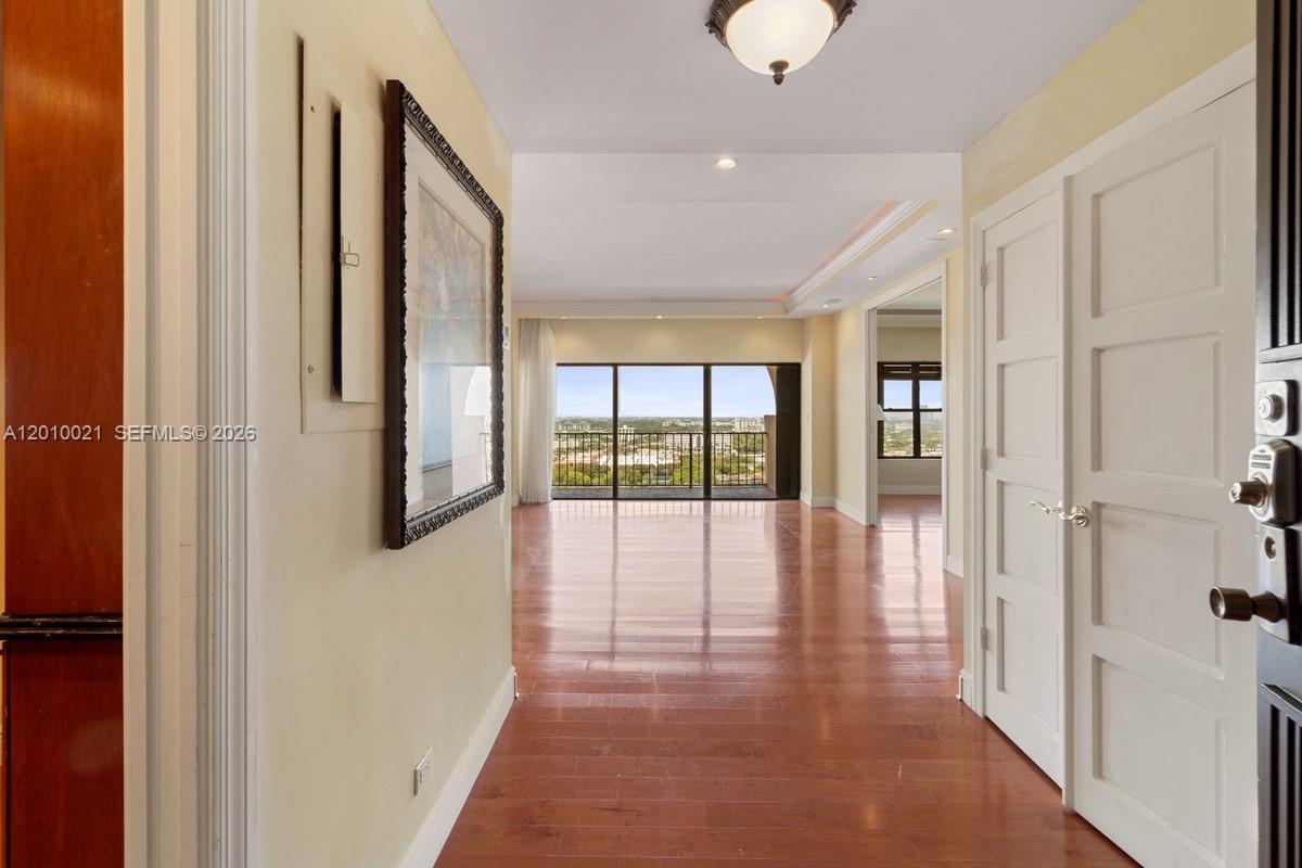 A hallway with hardwood floors leads to a living area with floor-to-ceiling windows — 1800 NE 114th St, Miami FL 33181, MIAMI, FL
