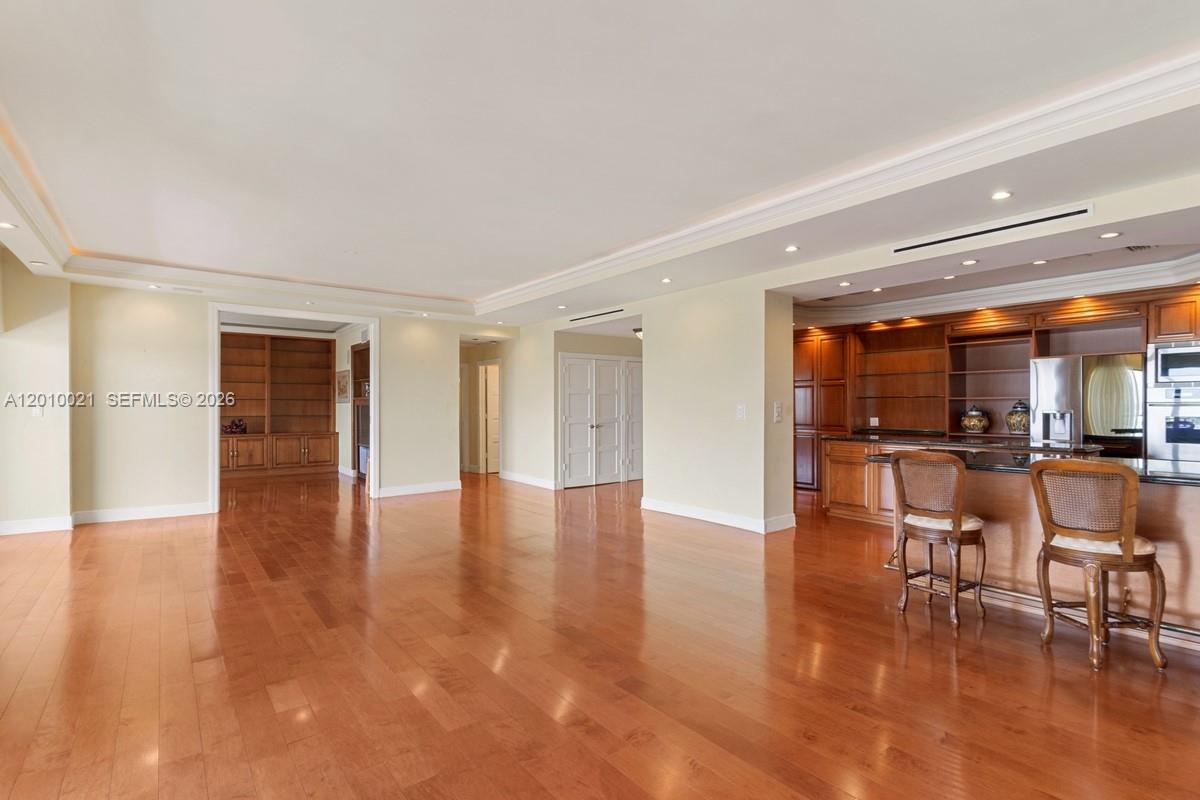 A spacious room features hardwood floors, recessed lighting, and a built-in wooden bar area — 1800 NE 114th St, Miami FL 33181, MIAMI, FL