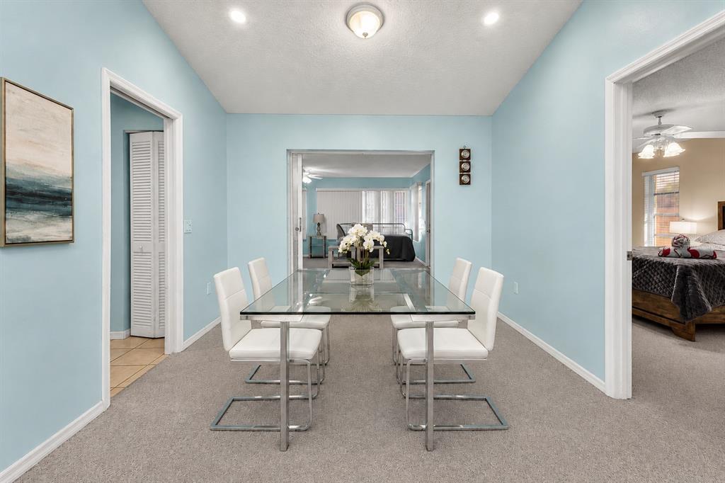 A dining room with a glass table, four white chairs, and light blue walls — 285 MARK TWAIN LANE, ROTONDA WEST, FL