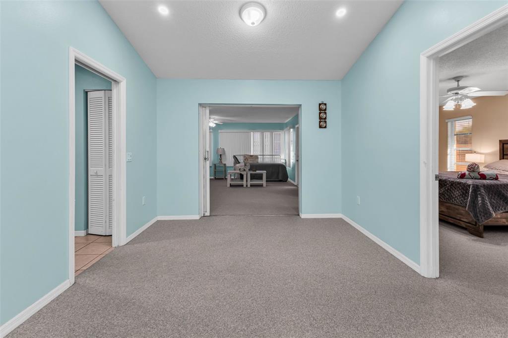 A carpeted room with light blue walls connects to a bedroom and a living area — 285 MARK TWAIN LANE, ROTONDA WEST, FL
