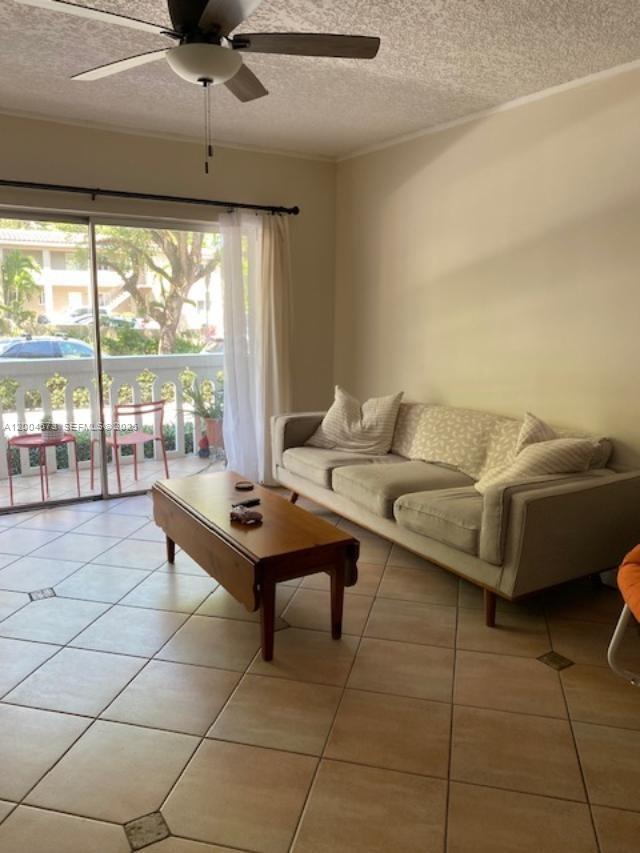 A living room features a beige sofa, a wooden coffee table, and a sliding glass door — 100 Edgewater Dr # 102, Coral Gables FL 33133, CORAL GABLES, FL