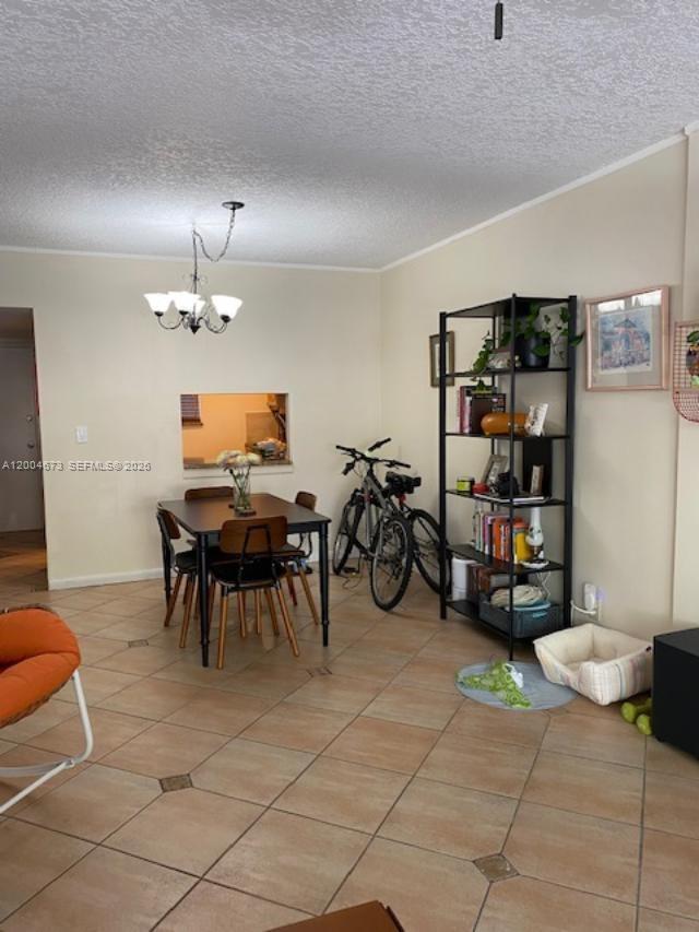 An empty room features beige tiled flooring with decorative insets and a kitchen pass-through window — 100 Edgewater Dr # 102, Coral Gables FL 33133, CORAL GABLES, FL