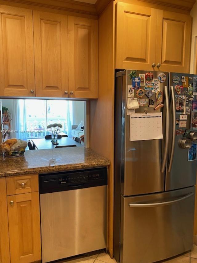 A kitchen features light wood cabinets, stainless steel appliances, and a pass-through to a dining area — 100 Edgewater Dr # 102, Coral Gables FL 33133, CORAL GABLES, FL