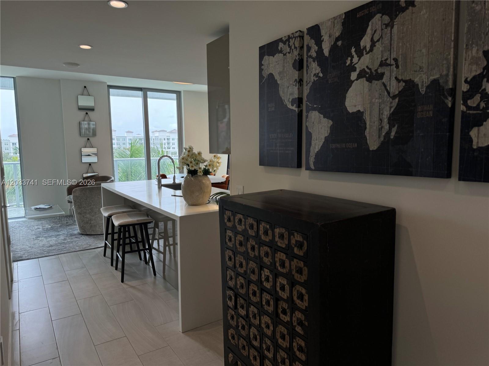A kitchen with a white island and bar stools sits near a wall with map art — 2000 Metropica Way # 417, Sunrise FL 33323, SUNRISE, FL