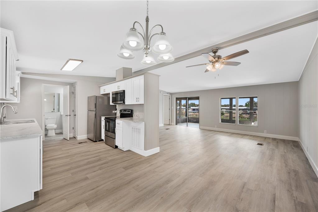 An open-concept kitchen and living area with light wood flooring and white cabinetry — 2055 S FLORAL AVENUE UNIT 117, BARTOW, FL