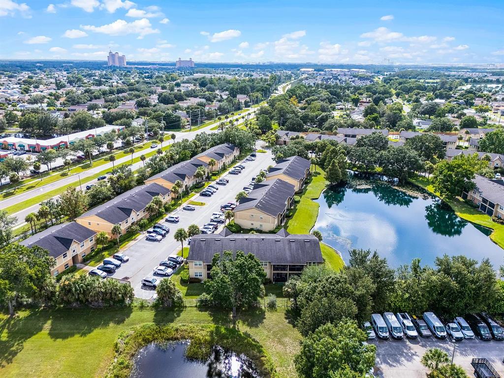 An aerial view shows apartment buildings, a pond, and parking lots in a suburban area — 2401 BARLEY CLUB DRIVE UNIT GE, ORLANDO, FL