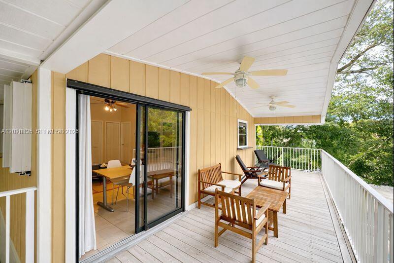 A covered wooden deck features outdoor furniture, ceiling fans, and sliding glass doors to an interior — 335 Bay View Ave, Key Largo FL 33037, KEY LARGO, FL