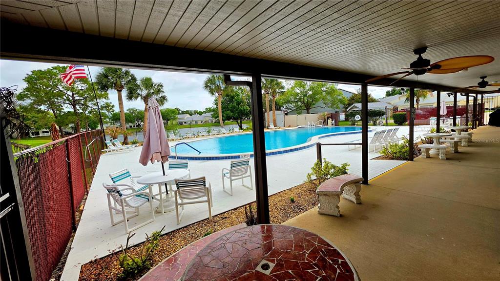 A covered patio overlooks a swimming pool surrounded by lounge chairs and palm trees — 2271 CANDLEWOOD LANE, NEW SMYRNA BEACH, FL