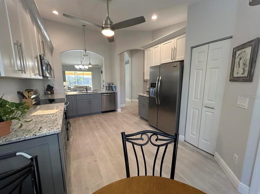 A kitchen features gray lower cabinets, white upper cabinets, stainless steel appliances, and wood-look flooring — 3701 ALBACETE CIRCLE UNIT 98, PUNTA GORDA, FL