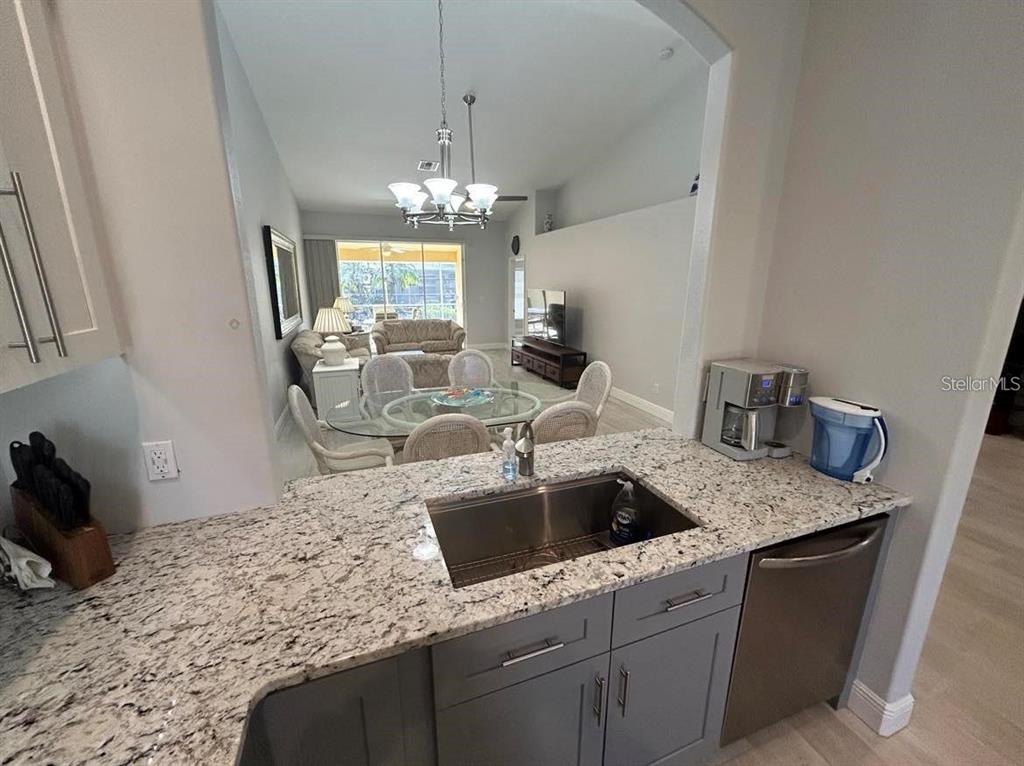 A kitchen sink and granite countertop overlook a dining area and living room — 3701 ALBACETE CIRCLE UNIT 98, PUNTA GORDA, FL