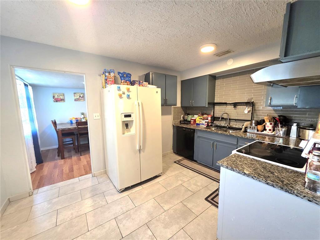 A kitchen features grey cabinets, a white refrigerator, and a tiled floor — 2137 4TH STREET E, BRADENTON, FL