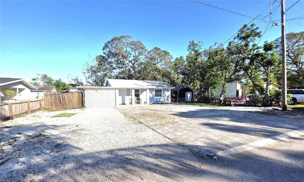 A light blue house with a paved driveway and gravel yard under a clear sky — 2137 4TH STREET E, BRADENTON, FL