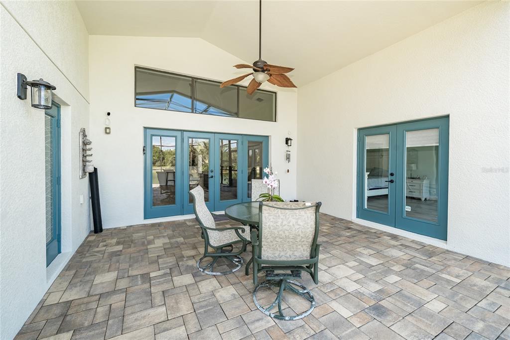 A covered patio features a paved floor, a ceiling fan, and blue-framed glass doors — 4907 POINTE O WOODS DRIVE, WESLEY CHAPEL, FL