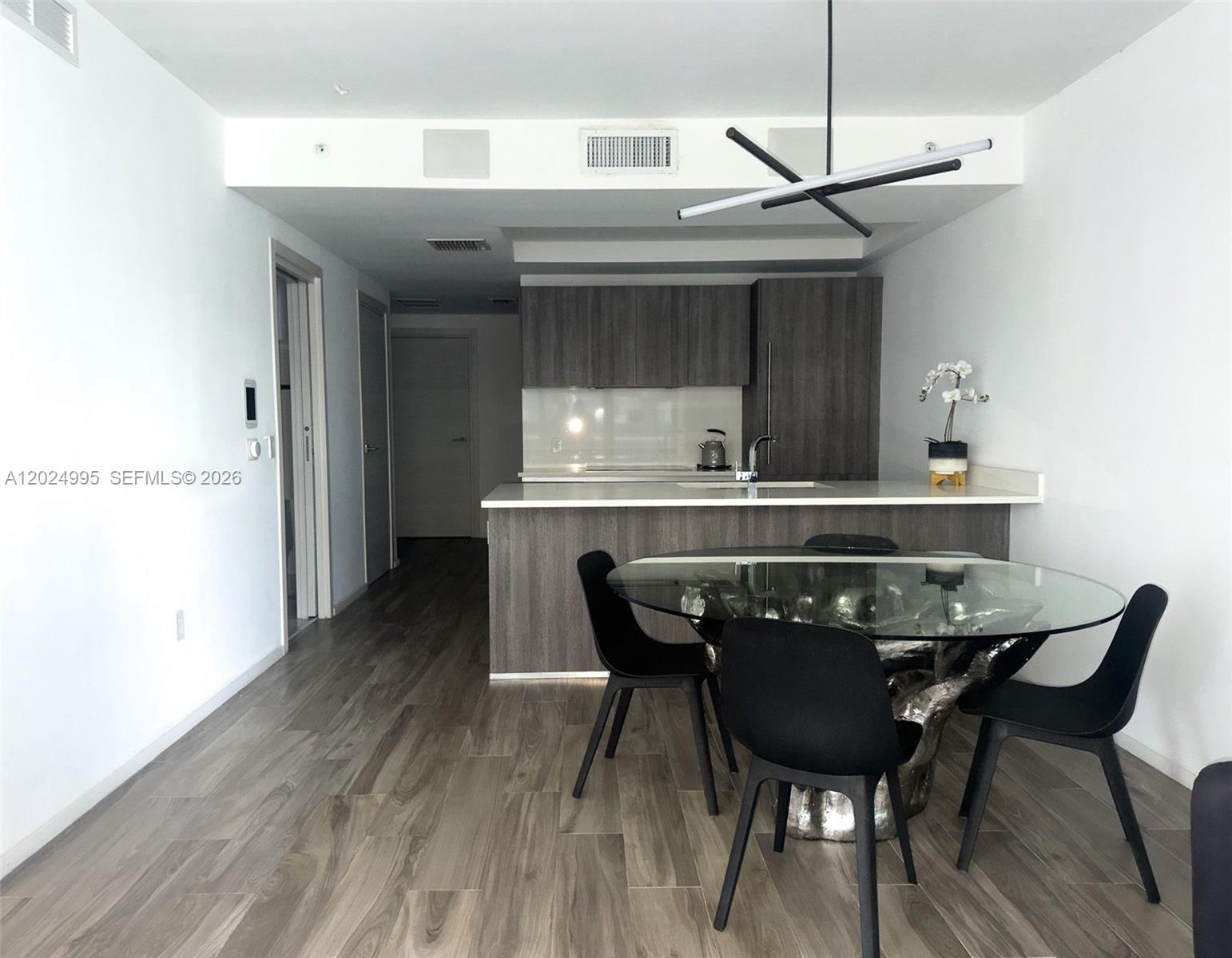 A modern kitchen with dark wood cabinets and a glass-topped dining table with black chairs — 801 S Miami Ave # 2607, Miami FL 33130, MIAMI, FL