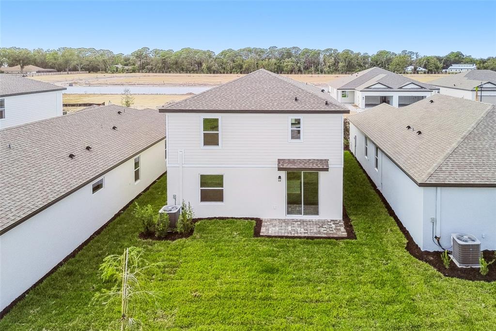 The rear exterior of a two-story house features a small patio and a grassy yard — 9118 OPTIMIST WAY, PALMETTO, FL