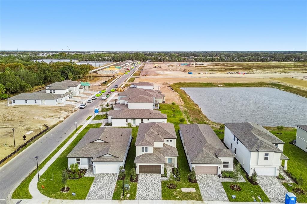 An aerial view shows a row of newly constructed suburban houses next to a pond — 9118 OPTIMIST WAY, PALMETTO, FL